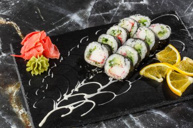 İçinde karides, salatalık ve krem peynir olan suşi rulosu. Maki Futomaki suşi rulosu ve siyah mermer arka planda karides. Suşi menüsü. Japon yemeği. Yatay fotoğraf.