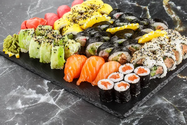 Japanese sushi set. Set of fresh tuna maki , salmon nigiri and dragon sushi rolls served on black plate close-up. Horizontal top view from above Top view flat lay. A set for a large company.