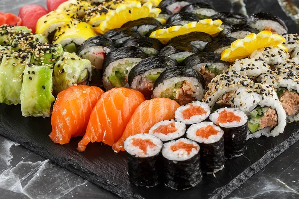 Japanese sushi set. Set of fresh tuna maki , salmon nigiri and dragon sushi rolls served on black plate close-up. Horizontal top view from above Top view flat lay. A set for a large company.