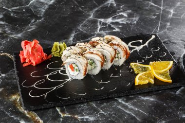 İçinde salatalık, domates, yılan balığı ve krem peynir olan suşi ruloları siyah mermer arka planda izole edilmiş. Philadelphia unagi rulosu. Suşi menüsü. Yatay fotoğraf.