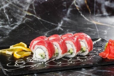 Siyah mermer zemin üzerinde salatalık, ton balığı ve krem peynirli suşi ruloları. Philadelphia usulü suşi ve karides. Suşi menüsü. Yatay fotoğraf.