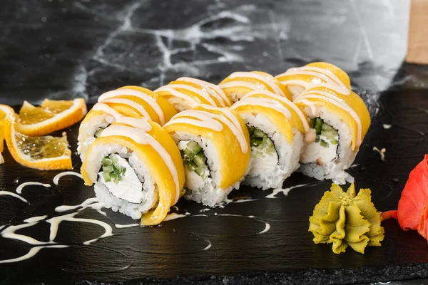 Sushi Rolls with processed cheese, cheddar, american cheese, avocado, mango and Cream Cheese inside on black slate isolated on black marble background. Philadelphia roll sushi with mango. Sushi menu.