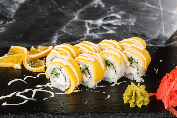Sushi Rolls with processed cheese, cheddar, american cheese, avocado, mango and Cream Cheese inside on black slate isolated on black marble background. Philadelphia roll sushi with mango. Sushi menu.