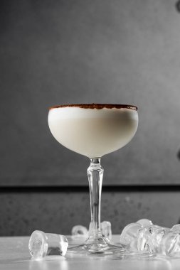 Bir bardak İrlanda kremalı likör, anason, kakao ve gri arka planda buz. Seçici odaklanma. Genel görünüm, kopyalama alanı. Kafe reklamı için. Bar menüsü. Dikey fotoğraf.