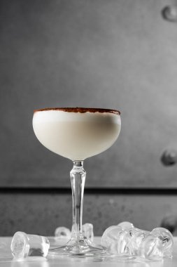 Bir bardak İrlanda kremalı likör, anason, kakao ve gri arka planda buz. Seçici odaklanma. Genel görünüm, kopyalama alanı. Kafe reklamı için. Bar menüsü. Dikey fotoğraf.