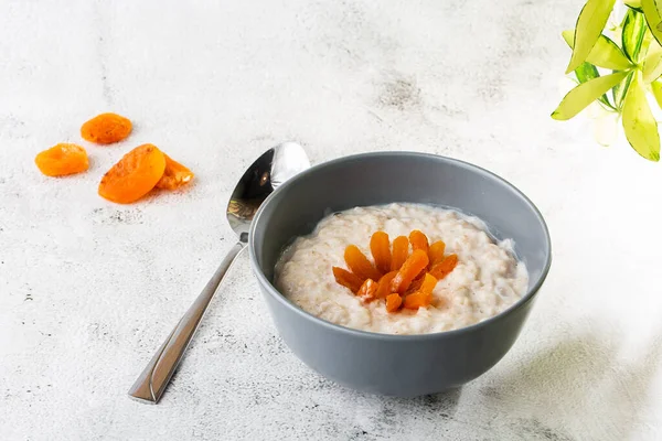 Avena gachas o gachas de avena o cereales de desayuno con albaricoques secos aislados sobre fondo de mármol blanco. Comida casera. Sabroso desayuno. Enfoque selectivo. Fotografía horizontal . — Foto de Stock