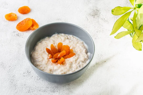 Avena gachas o gachas de avena o cereales de desayuno con albaricoques secos aislados sobre fondo de mármol blanco. Comida casera. Sabroso desayuno. Enfoque selectivo. Fotografía horizontal . — Foto de Stock