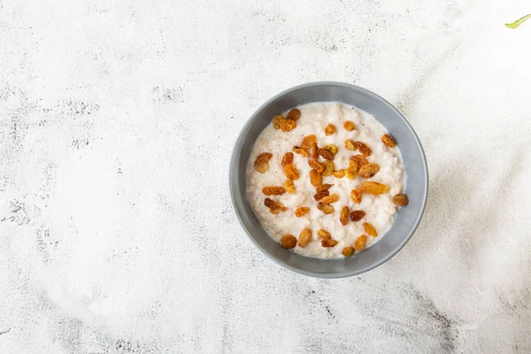 Avena gachas o gachas de avena o cereales de desayuno con pasas aisladas sobre fondo de mármol blanco. Comida casera. Sabroso desayuno. Enfoque selectivo. Fotografía horizontal . — Foto de Stock