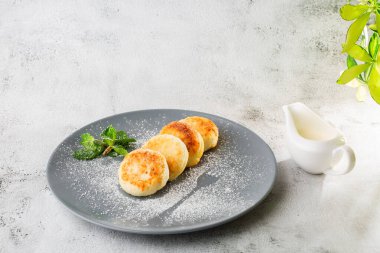 Süzme peynirli krep, Syrniki veya kremalı cheesecake, bal, beyaz mermer arka planda izole edilmiş nane. Ev yapımı yemek. Lezzetli bir kahvaltı. Seçici odaklanma. Hotizontal fotoğraf.