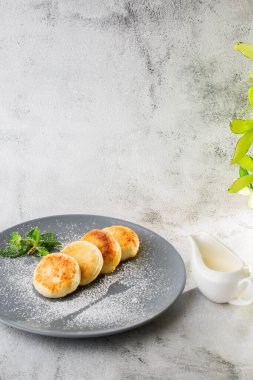 Süzme peynirli krep, Syrniki veya kremalı cheesecake, bal, beyaz mermer arka planda izole edilmiş nane. Ev yapımı yemek. Lezzetli bir kahvaltı. Seçici odaklanma. Dikey fotoğraf.