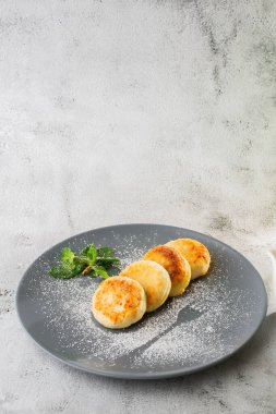 Süzme peynirli krep, Syrniki veya kremalı cheesecake, bal, beyaz mermer arka planda izole edilmiş nane. Ev yapımı yemek. Lezzetli bir kahvaltı. Seçici odaklanma. Dikey fotoğraf.