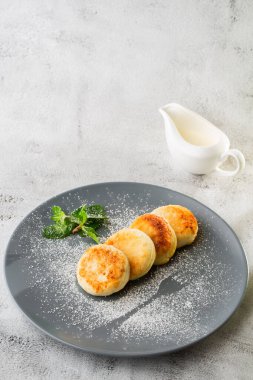 Süzme peynirli krep, Syrniki veya kremalı cheesecake, bal, beyaz mermer arka planda izole edilmiş nane. Ev yapımı yemek. Lezzetli bir kahvaltı. Seçici odaklanma. Dikey fotoğraf.