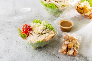 Tavuk salatası. Tavuk Sezar Salatası. Sezar salatası ve ızgara tavuk. Izgara tavuk göğsü, domates, plastik tabakta taze salata. Beyaz mermer arka planda izole edilmiş. Ev yapımı yemek. Teşekkürler.