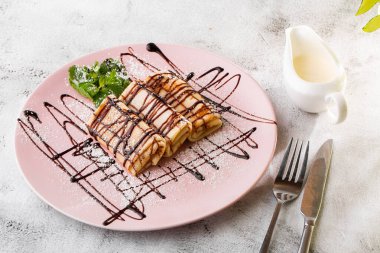 Beyaz mermer arka planda izole edilmiş çikolata soslu krepler. Ev yapımı yemek. Lezzetli bir kahvaltı. Seçici odaklanma. Hotizontal fotoğraf.