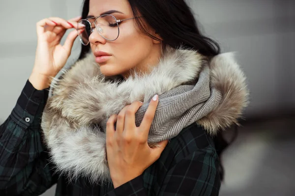 Outdoor close up fashion portrait of young beautiful confident woman wearing trendy shirt, white scarf and sunglasses Beautiful woman in luxury fur shawl. Advertising for sunglasses shop. Copy space.