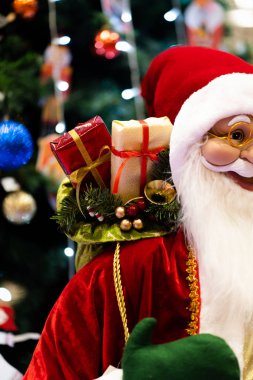 Mutlu Noeller ve mutlu yıllar Noel Baba bebeği. Noel festivalinde lambalı, fotokopi uzayı. Kırmızı kostümlü şirin büyükbaba Frost ve ağaç zemininde yeşil eldivenler. hediye ve kutlama.