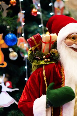 Mutlu Noeller ve mutlu yıllar Noel Baba bebeği. Noel festivalinde lambalı, fotokopi uzayı. Kırmızı kostümlü şirin büyükbaba Frost ve ağaç zemininde yeşil eldivenler. hediye ve kutlama.