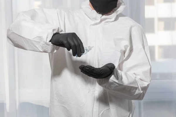 Doctor en traje de PPE uniforme y guantes trata las manos con antiséptico. Brote de Coronavirus. Concepto de cuarentena Covid-19. médico y atención médica. Equipo de protección personal Stop virus . — Foto de Stock