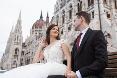 Gelin ve damat eski kasaba caddesinde sarılıyor. Düğün çifti Budapeşte 'de Parlamento Binası yakınlarında oturuyor. Kafkasyalı mutlu romantik çift evliliklerini kutluyor. Düğün ve aşk konsepti.