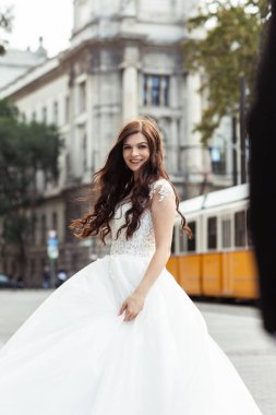 Eski şehir sokağındaki gelin. Düğün Budapeşte 'de Parlamento Binası yakınlarında. Kafkasyalı mutlu romantik kadın evliliğini kutluyor. Düğün ve aşk konsepti.