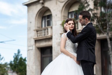 Gelin ve damat eski kasaba caddesinde sarılıyor. Düğün çifti Budapeşte 'de Parlamento Binası yakınlarında yürüyor. Kafkasyalı mutlu romantik çift evliliklerini kutluyor. Düğün ve aşk konsepti.