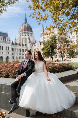 Gelin ve damat eski kasaba caddesinde sarılıyor. Düğün çifti Budapeşte 'de Parlamento Binası yakınlarında oturuyor. Kafkasyalı mutlu romantik çift evliliklerini kutluyor. Düğün ve aşk konsepti.