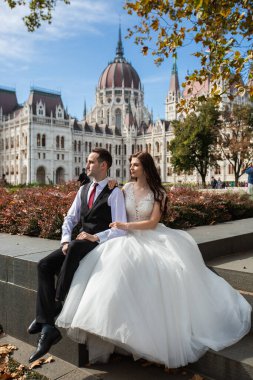 Gelin ve damat eski kasaba caddesinde sarılıyor. Düğün çifti Budapeşte 'de Parlamento Binası yakınlarında oturuyor. Kafkasyalı mutlu romantik çift evliliklerini kutluyor. Düğün ve aşk konsepti.