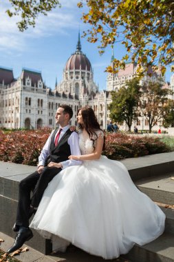 Gelin ve damat eski kasaba caddesinde sarılıyor. Düğün çifti Budapeşte 'de Parlamento Binası yakınlarında oturuyor. Kafkasyalı mutlu romantik çift evliliklerini kutluyor. Düğün ve aşk konsepti.