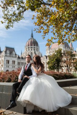 Gelin ve damat eski kasaba caddesinde sarılıyor. Düğün çifti Budapeşte 'de Parlamento Binası yakınlarında oturuyor. Kafkasyalı mutlu romantik çift evliliklerini kutluyor. Düğün ve aşk konsepti.