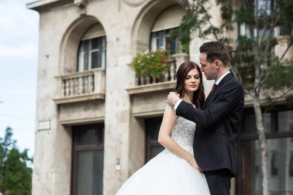 Bruid en bruidegom knuffelen in de oude stad straat. Bruidspaar loopt in Boedapest in de buurt van Parliament House. Kaukasisch gelukkig romantisch jong koppel vieren hun huwelijk. Bruiloft en liefde concept. — Stockfoto