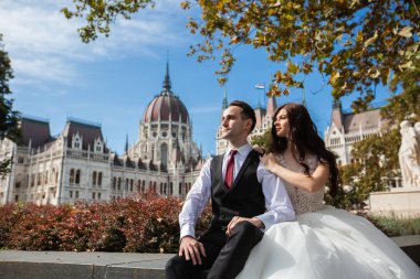 Gelin ve damat eski kasaba caddesinde sarılıyor. Düğün çifti Budapeşte 'de Parlamento Binası yakınlarında oturuyor. Kafkasyalı mutlu romantik çift evliliklerini kutluyor. Düğün ve aşk konsepti.