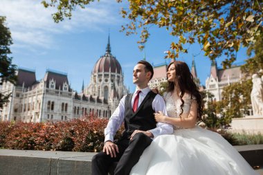 Gelin ve damat eski kasaba caddesinde sarılıyor. Düğün çifti Budapeşte 'de Parlamento Binası yakınlarında oturuyor. Kafkasyalı mutlu romantik çift evliliklerini kutluyor. Düğün ve aşk konsepti.