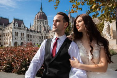 Gelin ve damat eski kasaba caddesinde sarılıyor. Düğün çifti Budapeşte 'de Parlamento Binası yakınlarında oturuyor. Kafkasyalı mutlu romantik çift evliliklerini kutluyor. Düğün ve aşk konsepti.