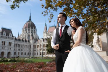 Gelin ve damat eski kasaba caddesinde sarılıyor. Düğün çifti Budapeşte 'de Parlamento Binası yakınlarında yürüyor. Kafkasyalı mutlu romantik çift evliliklerini kutluyor. Düğün ve aşk konsepti.