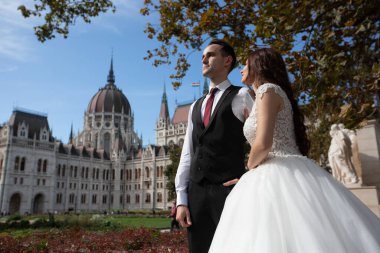 Gelin ve damat eski kasaba caddesinde sarılıyor. Düğün çifti Budapeşte 'de Parlamento Binası yakınlarında yürüyor. Kafkasyalı mutlu romantik çift evliliklerini kutluyor. Düğün ve aşk konsepti.