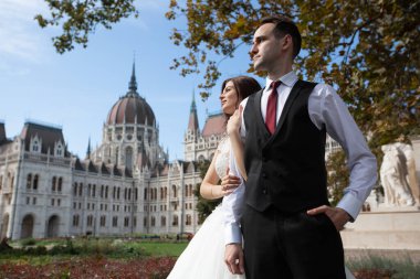 Gelin ve damat eski kasaba caddesinde sarılıyor. Düğün çifti Budapeşte 'de Parlamento Binası yakınlarında yürüyor. Kafkasyalı mutlu romantik çift evliliklerini kutluyor. Düğün ve aşk konsepti.