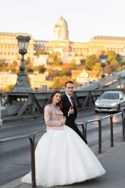 Gelin ve damat eski kasaba caddesinde sarılıyor. Macaristan 'da Szechenyi Zincir Köprüsü' nde yürüyen düğün çifti. Evliliklerini kutlayan mutlu romantik genç çift. Düğün ve aşk konsepti.