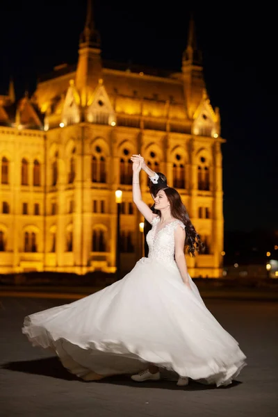 Novia y novio abrazándose en la calle del casco antiguo. Boda pareja paseos en Budapest cerca de la Casa del Parlamento en la noche. Feliz pareja romántica joven celebrando su matrimonio. Boda y amor concepto . — Foto de Stock