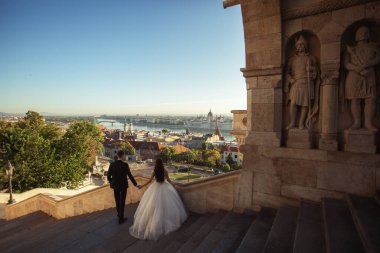 Gelin ve damat eski kasaba caddesinde sarılıyor. Budapeşte, Macaristan 'da Balıkçı Kalesi' nde yürüyen düğün çifti. Evliliklerini kutlayan mutlu romantik genç çift. Düğün ve aşk konsepti.