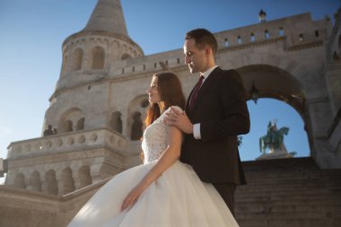 Gelin ve damat eski kasaba caddesinde sarılıyor. Budapeşte, Macaristan 'da Balıkçı Kalesi' nde yürüyen düğün çifti. Evliliklerini kutlayan mutlu romantik genç çift. Düğün ve aşk konsepti.