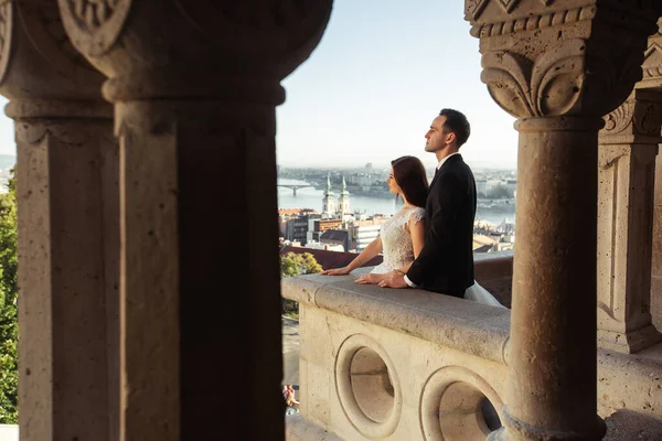 Bruid en bruidegom knuffelen in de oude stad straat. Bruidspaar wandelend op het Fishermans Bastion, Boedapest, Hongarije. Gelukkig romantisch jong stel vieren hun huwelijk. Bruiloft en liefde concept. — Stockfoto