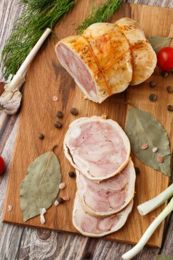 Ahşap arka planda izole edilmiş marul yaprağı desenli ızgara tavuklu rulo. Taze et ve kısmen dilimlenmiş. Tavuklu jambon ve lezzetli tavuk eti.