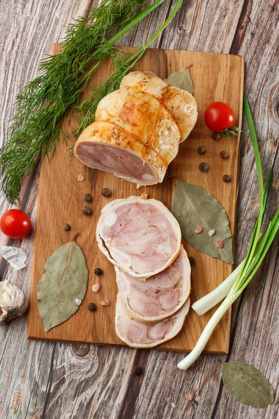 Ahşap arka planda izole edilmiş marul yaprağı desenli ızgara tavuklu rulo. Taze et ve kısmen dilimlenmiş. Tavuklu jambon ve lezzetli tavuk eti.