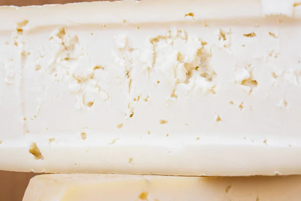 Slice of hard cheese, goat\'s milk. Typical soft texture and whitish color.