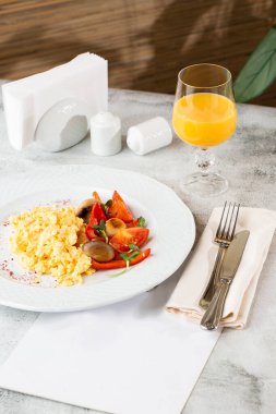 Beyaz mermer zemine izole edilmiş, içi ıspanaklı, kiraz domatesli omlet ve taze portakal suyu. Ev yapımı yemek. Lezzetli bir kahvaltı. Seçici odaklanma. Dikey fotoğraf.