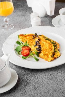 Peynirli omlet, vişneli domates ve beyaz mermer arka planda izole edilmiş ekşi ekmek. Ev yapımı yemek. Lezzetli bir kahvaltı. Seçici odaklanma. Dikey fotoğraf.