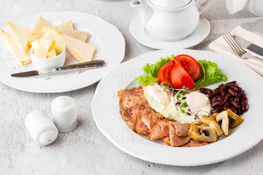 Haşlanmış yumurta, sebze, jambon, domates, kırmızı fasulye ve beyaz mermer arka planda izole edilmiş ekşi ekmek. Ev yapımı yemek. Lezzetli bir kahvaltı. Seçici odak.