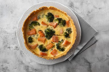 Kiş turtası, en iyi manzara. Yukarıdan bak. Klasik somon ve brokolili kiş brokoli çiçekli kısa hamurlu hamur tatlısı ve masada kremalı yumurta kremalı somon füme..