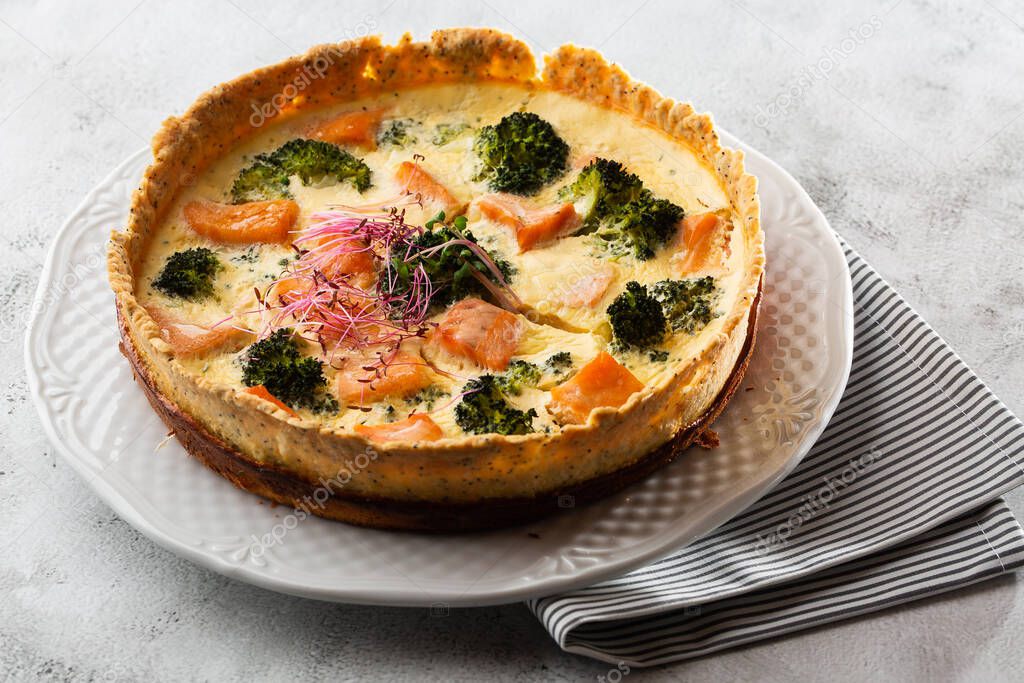 quiche tart, top view. view from above. Classic salmon and broccoli quiche made from shortcrust pastry with broccoli florets and smoked salmon in a creamy free range egg custard close-up on the table.