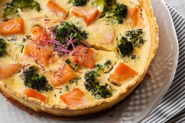 Kiş turtası, en iyi manzara. Yukarıdan bak. Klasik somon ve brokolili kiş brokoli çiçekli kısa hamurlu hamur tatlısı ve masada kremalı yumurta kremalı somon füme..